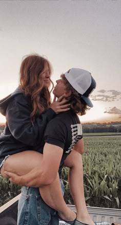 a man and woman hug in the back of a pick up truck on a farm