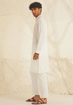 Presenting an exquisite Porcelain White Silk Kurta Set, featuring a sophisticated Chinese collar, elegant metallic silver buttons, and intricate hand-embroidered detailing on the neckline and sleeves. Paired with trendy white pants, this ensemble is perfect for engagements, Roka ceremonies, or puja events, combining timeless elegance with contemporary style. Composition : Dupion Silk Care: Dry Clean Only and Vacuum Storage This product can be customized for sleeves, length and colour Delivery : 4-6 weeks as the product is hand crafted. Check Size Guide or choose MySize for free customisation (All Sizes above XL can be made at 15% additional cost) For more information and sizes please contact fabiliciousfashion@gmail.com or visit our Copenhagen studio. About the Designer : Shreyansh, a dist Elegant Semi-formal Sets For Eid, Classic Long Sleeve Traditional Formal Wear, Festive Kurta With Set-in Sleeves, Fitted Kurta With Set-in Sleeves For Festive Occasions, Classic Unstitched Traditional Wear For Formal Occasions, Classic Fitted Kurta For Festive Occasions, Classic Long Sleeve Festive Traditional Wear, Elegant Straight Kurta With Set-in Sleeves, Elegant Off-white Straight Kurta Traditional Wear