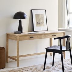 a wooden desk with two black lamps and a framed photograph on the wall next to it