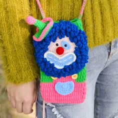 a close up of a person wearing a crocheted bag with a clown face on it