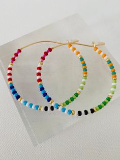 Colorful glass rainbow beads adorn a gold hoop earring. These lightweight earrings are so versatile. Cheap Multicolor Beaded Earrings For Beach, Trendy Beaded Earrings, Trendy Colorful Beaded Hoop Earrings For Gifts, Multicolor Beaded Jewelry For Everyday, Multicolor Beaded Everyday Jewelry, Trendy Multicolor Beaded Earrings With Tiny Beads, Colorful Round Beads Earrings For Everyday, Multicolor Beaded Earrings With Dangling Beads For Everyday, Colorful Beaded Earrings For Everyday