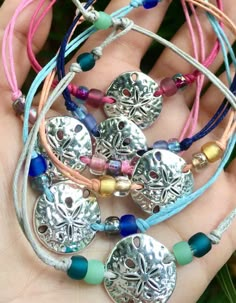 a hand holding several bracelets with charms on it's sides and beads in the middle