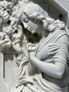 a white statue with long hair and flowers on it