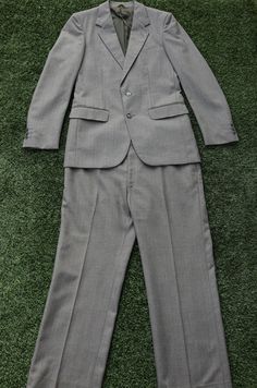 This vintage 1970s Sandy Grey Suit is not only super stylish, unique and timeless but it is also in amazing condition. The suit includes both a jacket and pants.  The jacket features a typical 70s style collar, has interior shoulder pads, 2 buttons down the front, has a beautiful  grey lining, has 3 front pockets, 2 interior pockets, and also has 3 smaller buttons on each sleeve cuff. The pants are high waisted, with 2 front pockets and 2 back pockets. They also have darts that run down the front of the pants, have a working zip up fly, with clasp closure, and also has belt loops. Please note that these pants have a tiny mark on the front of the pant leg. It is a tiny dot mark. It is barley noticeable, however worth mentioning. This tiny mark can be seen in the final image shown above.  Fa Spring Vintage Tailored Suits, Retro Fitted Formal Sets, Retro Fitted Sets For Formal Occasions, Retro Fitted Single Breasted Suits, Retro Fitted Suits For Spring, Retro Fitted Spring Suits, Spring Retro Fitted Suits, Vintage Suits For Spring Workwear, Tailored Retro Suits For Workwear