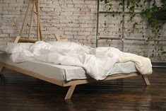 an unmade bed sitting in front of a brick wall