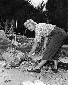 an old black and white photo of a woman digging through rubble