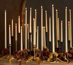 a bunch of candles that are next to each other with ribbons on the table in front of them