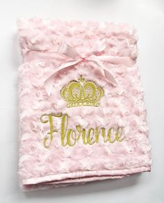 a pink blanket with gold lettering and a crown on it that says florence