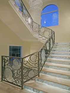 an elegant staircase with chandelier and glass railing