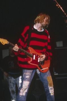 a man in striped shirt playing an electric guitar