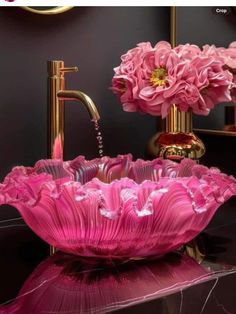 a pink glass bowl sink sitting on top of a counter next to a gold faucet