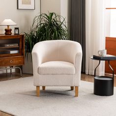 a white chair sitting on top of a rug next to a table and potted plant