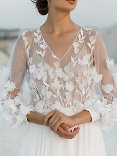 a woman wearing a white dress with flowers on it