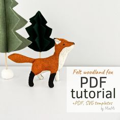 a felt woodland fox is standing next to a small pine tree and the words felt woodland fox are in front of it