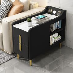 a white couch sitting next to a black and gold end table with books on it