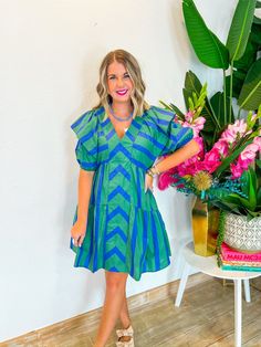 This playful mini dress combines blue and green in a charming chevron and stripe pattern, complete with a front panel and tiered ruffle seams. The ruffle sleeves and V-neckline add a touch of flirtiness, perfect for showing off your favorite necklaces. Whether you're heading to a weekend brunch or an outdoor concert, this dress has the perfect length for all heights. Style it with strappy sandals and a wide-brim hat for a chic, summery look! PRODUCT FIT - TRUE TO SIZE MODEL DETAILS - BRENNA IS A Green Summer Tiered Dress, Spring Green Tiered Dress For Beach, Striped Ruffled Mini Dress For Vacation, Chic Green Mini Dress With Ruffle Sleeves, Green Summer Tiered Beach Dress, Green Tiered Summer Mini Dress, Green Tiered Summer Dress, Green Ruffle Sleeve Mini Dress For Spring, Green Tiered Vacation Dress