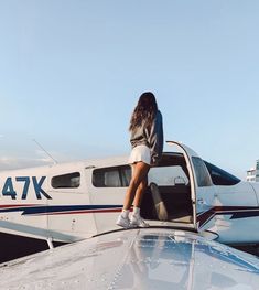 a woman sitting on the hood of an airplane