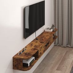 a flat screen tv mounted to the side of a wooden shelf next to a window