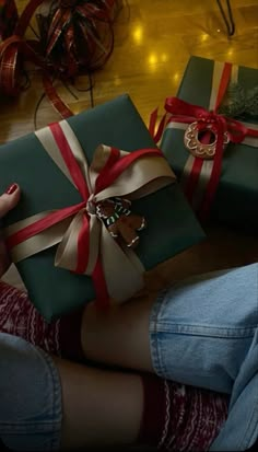 a woman sitting on the floor with two wrapped presents in front of her, both holding hands