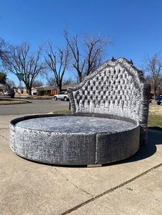 a large round bed sitting on top of a cement slab next to a parking lot