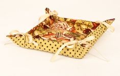 a yellow and brown polka dotty tray with decorative designs on the sides, tied in white ribbon