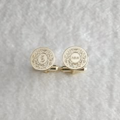 two gold cufflinks with an emblem on them