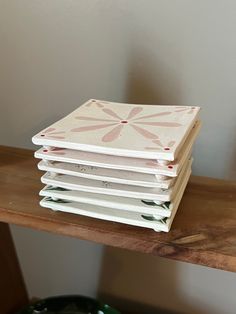 a stack of notebooks sitting on top of a wooden table next to a potted plant