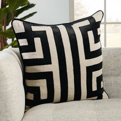 a black and white pillow sitting on top of a couch next to a plant in a living room