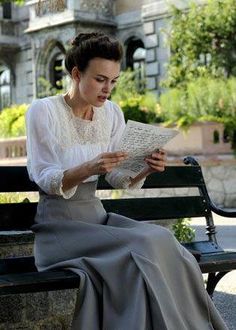 a woman sitting on a bench reading a paper