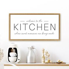 a kitchen sign on the wall above a coffee maker and other kitchen items in front of it