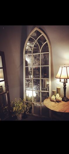 a room with a table, mirror and lamp on the wall next to an arched window