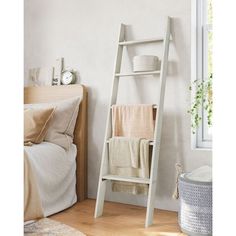 a white ladder leaning up against a wall next to a bed with pillows and blankets on it