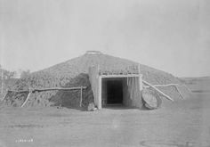 an old black and white photo of a hut in the desert