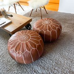 two brown poufles sitting on top of a carpeted floor next to a coffee table