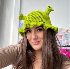 a woman wearing a green crocheted hat with a turtle on it's head