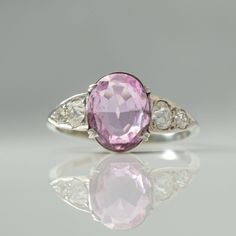 Fabulous Art Deco Pink Topaz Ring circa 1920 Featuring an Oval pink topaz which measures approx 1.75 carats, with three old cut diamonds to the shoulders, measuring approx .20 carats each side,  H colour and VS clarity. The topaz is set with four double claws on a raised pierced out mount, leading to a plain band shank and measures 9.5mm in width.  To the reverse the topaz and diamonds are set in an open backed setting which allows the light to shine through. This lovely ring would make the perf Pink Brilliant Cut Amethyst Wedding Ring, Wedding Pink Brilliant Cut Amethyst Ring, Classic Pink Topaz Ring For Anniversary, Pink Sapphire Ring In Platinum For Anniversary, Pink Sapphire Ring In Platinum For Wedding, Pink Sapphire Platinum Ring For Anniversary, Pink Sapphire Platinum Ring For Wedding, Vintage Pink Diamond Ring Hallmarked, Vintage Pink Diamond Ring With Hallmark