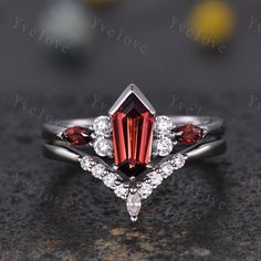 an engagement ring with two pear shaped red garnets and three white diamonds on top