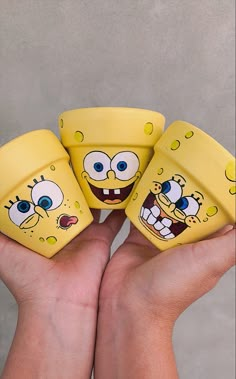 three yellow spongebob dices with faces painted on them in the palm of someone's hand