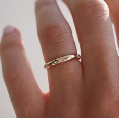 a woman's hand with a gold ring on top of her finger and diamond band