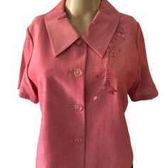 a woman's pink shirt with flowers and beads on the collar, front view