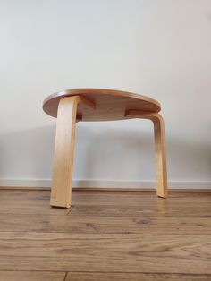 a wooden table sitting on top of a hard wood floor next to a white wall