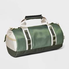 a green and white duffel bag sitting on top of a white floor next to a wall