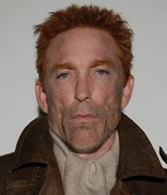 a man with freckled hair wearing a brown jacket