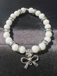 a white beaded bracelet with a bow charm