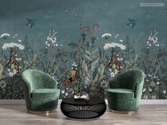 two green chairs sitting in front of a wall with flowers and birds painted on it