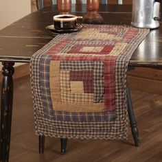 a table with a coffee pot on top of it and a quilted runner around the edge