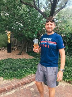 a man standing in front of a tree holding a drink