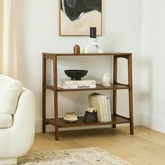 a white couch sitting next to a table with books on it and a painting above it