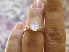 This is an oval moonstone ring, vintage style moonstone engagement ring, solitaire ring, moonstone engagement ring, gemstone ring, moonstone gold ring, oval engagement ring, a perfect moonstone engagement ring. This vintage style floral ring and has a dainty and feminine design, a solitaire vintage style with a natural oval rainbow moonstone, that symbolizes passion and endless love. This unique engagement ring is the best way to show your pure love for the one you love. ♥ Moonstone Gemstone mea Elegant Moonstone Cabochon Ring, Elegant Cabochon Moonstone Ring, Elegant Moonstone Cabochon Ring For Anniversary, Elegant Cabochon Moonstone Ring For Anniversary, Heirloom White Moonstone Ring With Rose Cut Diamonds, Moonstone Cabochon Ring For Anniversary, Elegant White Moonstone Ring, Oval Cabochon, Oval Moonstone Gemstone Ring, Elegant White Moonstone Ring With Oval Cabochon