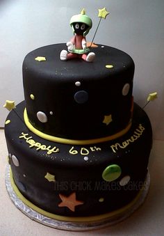 a black and yellow birthday cake with an astronaut on top, stars and moon decorations